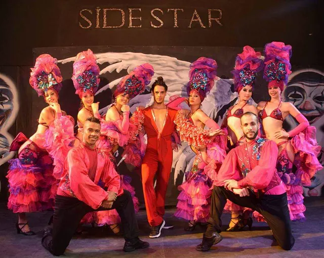 Elenco de cabaret cubano en Side Star, con bailarinas de plumas y Maikel de rodillas delante